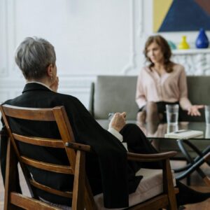 Man in Black Jacket Sitting on Brown Wooden Chair