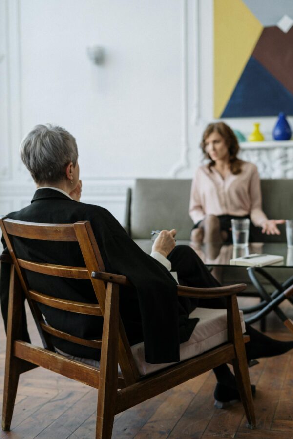 Man in Black Jacket Sitting on Brown Wooden Chair